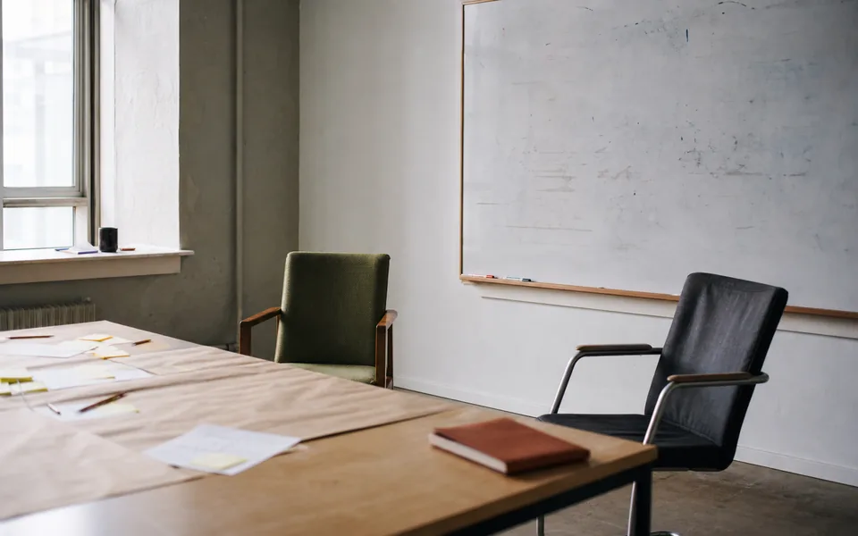 An unoccupied workshop room with notes, pencils, and a half-erased whiteboard.